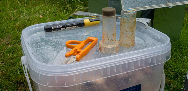 A plastic box with a pair of scissors and a yellow pen on the lid