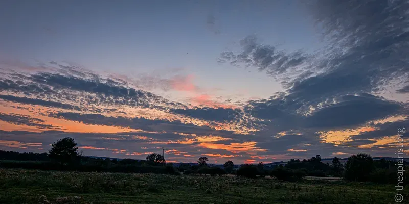 Last light on a late August evening, looking west with clouds and an orange sky