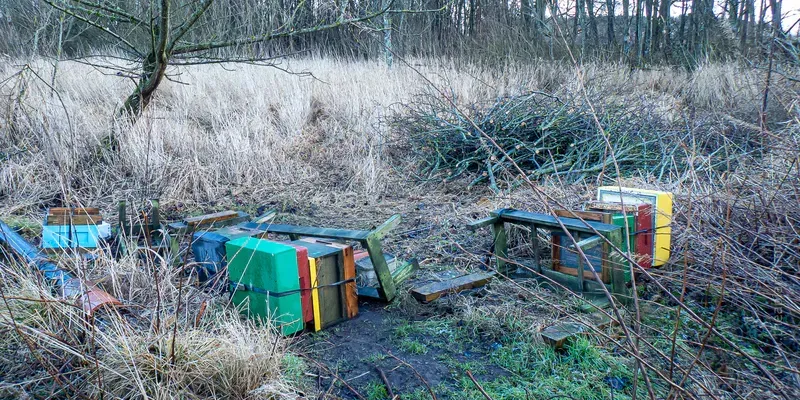 A photograph of bee hives and stands all knocked over after storm damage