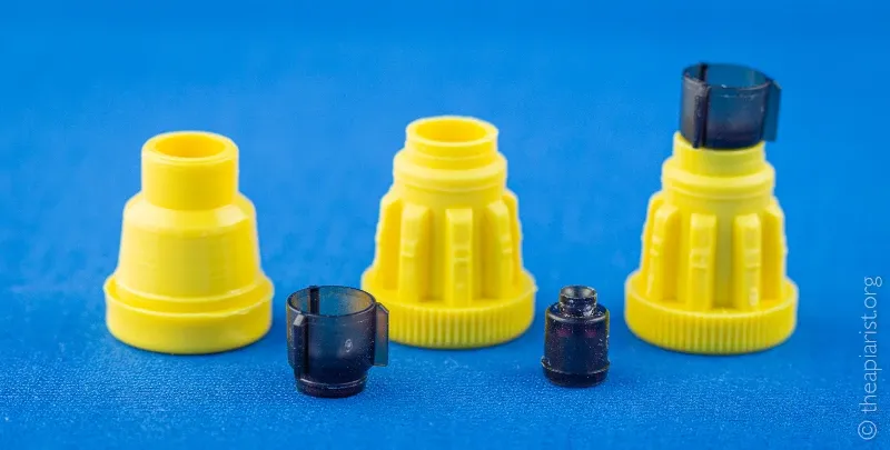Yellow plastic cup holders and plastic queen cup components against a blue background