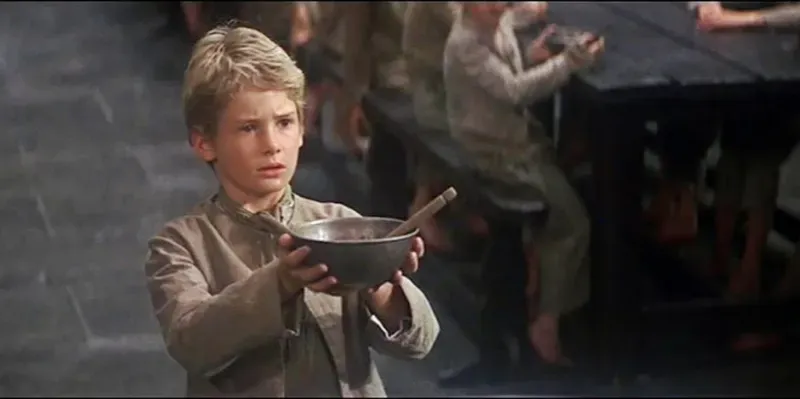 Photo from the film Oliver! of Oliver Twist asking for more gruel from the Master