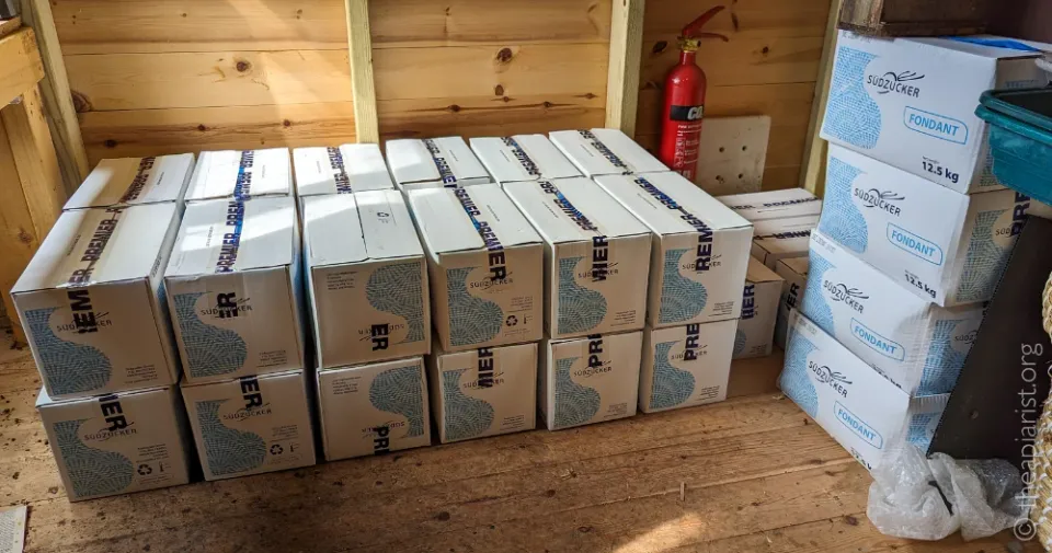 A stack of white cardboard boxes containing fondant stacked up in a wooden shed.